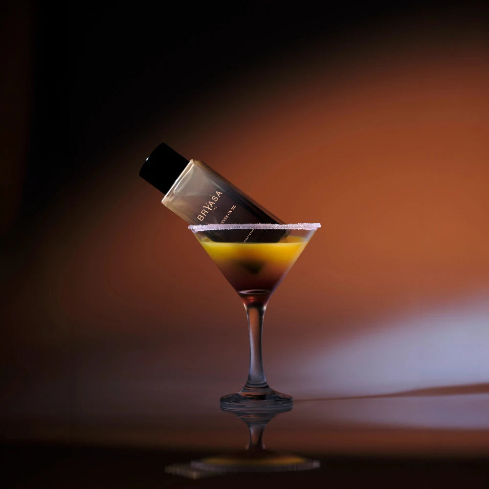 packshot du parfum de niche bryasa all on me dans un verre de cocktail avec un arrière plan type couché de soleil en californie