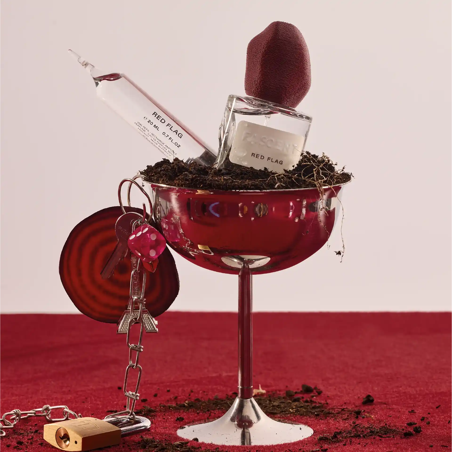parfum de niche red flag de la maison fascent dans un décord rouge avec le parfum dans un verre argenté