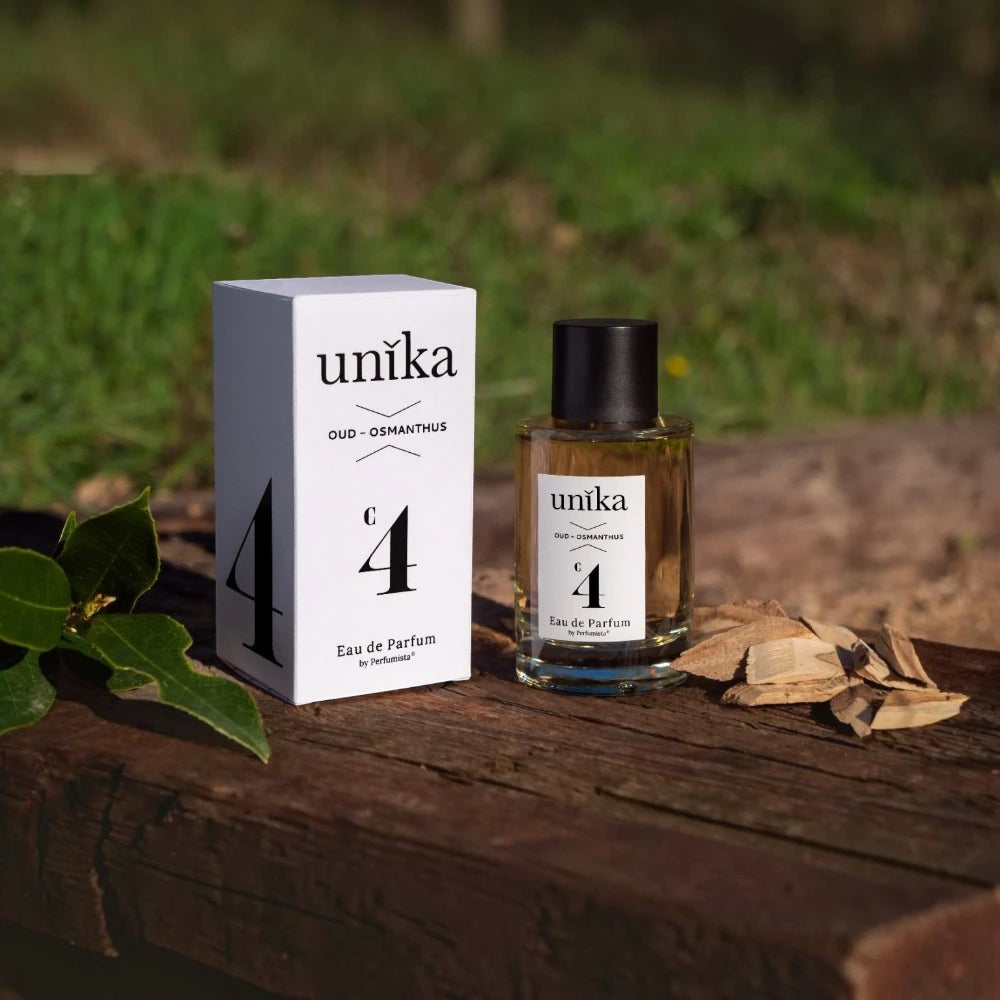 Unika N°4 Oud Osmanthus – Fruité Cuiré Oriental Tunisie sur du bois avec du bois de oud et une feuille d'osthmenthus