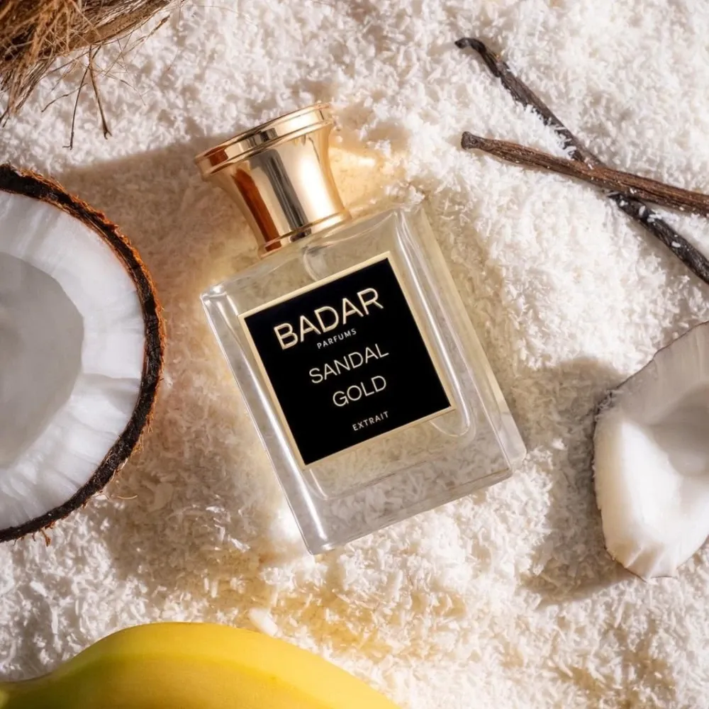 parfum de niche sandal gold de la maison Badar Parfum dans un fond de poudre coco et des gousses de vanille et de la banane