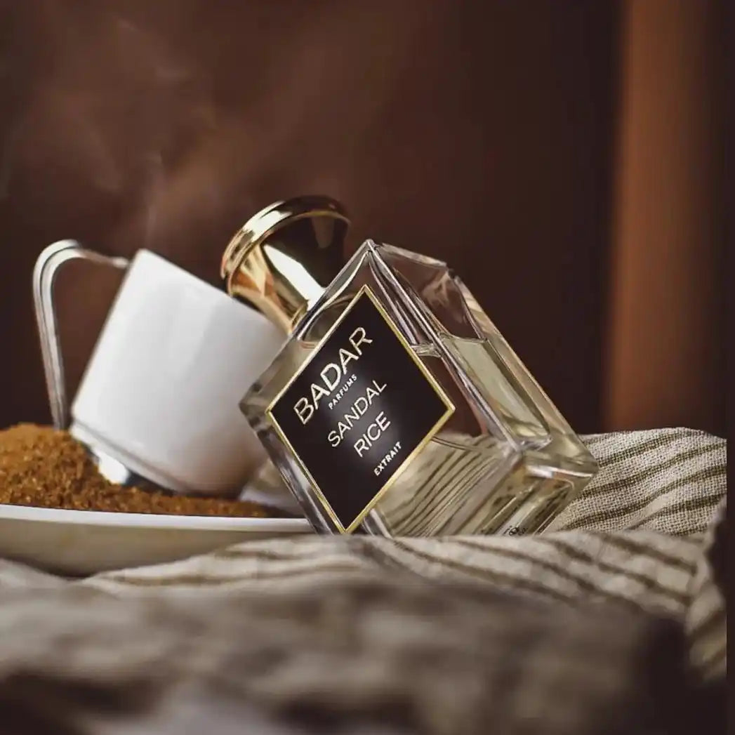 Flacon Sandal Rice de la Maison Badar Parfums sur une nappe de table, avec le flacon penché sur une tasse de café